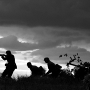 black and white photo of soldiers cautiously walking with guns through a field Image by Rozbooy from Pixabay